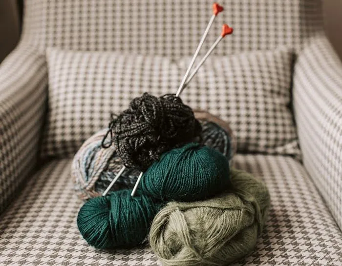 A comfortable armchair with colourful balls of yarn and knitting needles