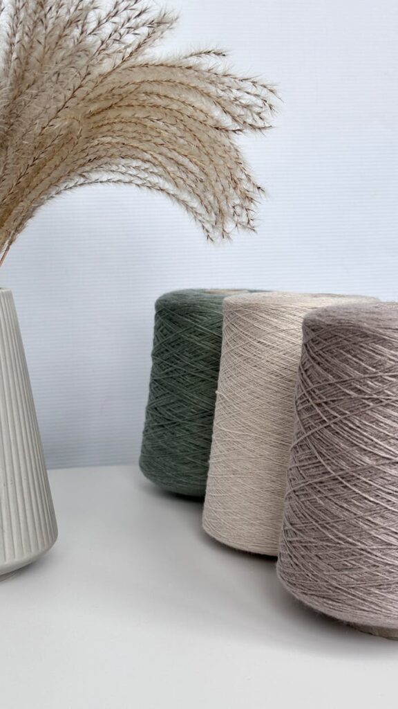 Aesthetic arrangement of yarn cones and pampas grass in a modern setting.