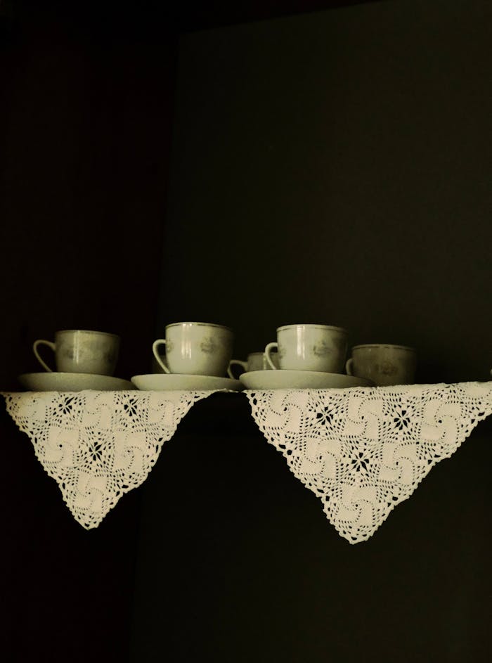 Aesthetic arrangement of vintage teacups on lace-draped shelves, creating a classic look.